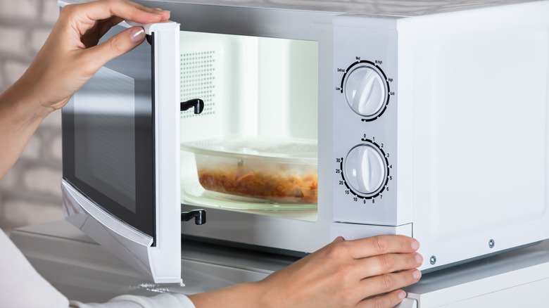 woman putting food in microwave