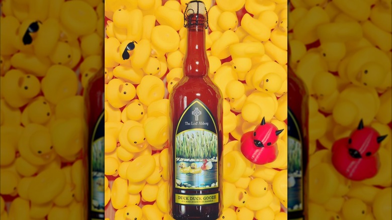 A bottle of The Lost Abbey's Duck Duck Gooze on a pile of yellow rubber ducks, with one small red devil duck.