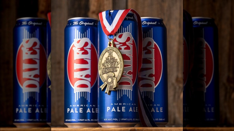 A Great American Beer Festival gold medal hanging over a row of tall blue cans of Oskar Blues Dale's Pale Ale.
