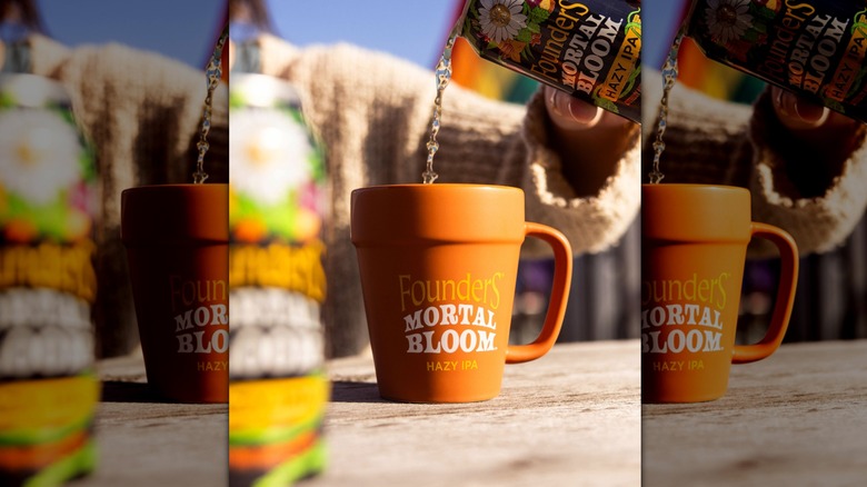 A hand pouring a can of Founders Brewing Company's Mortal Bloom Hazy IPA into a mug