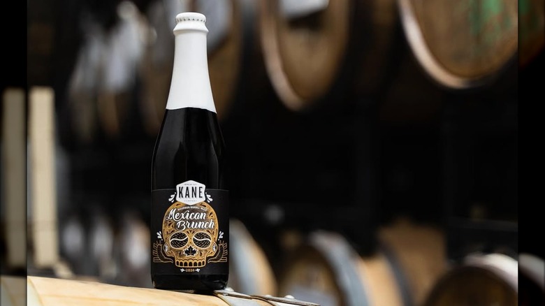 A bottle of Kane Brewing's Mexican Brunch sitting on a bourbon barrel