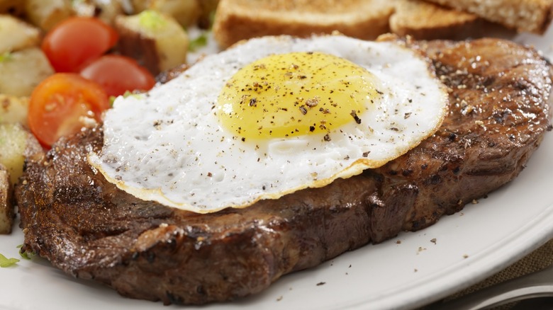 Steak topped with fried egg and black pepper