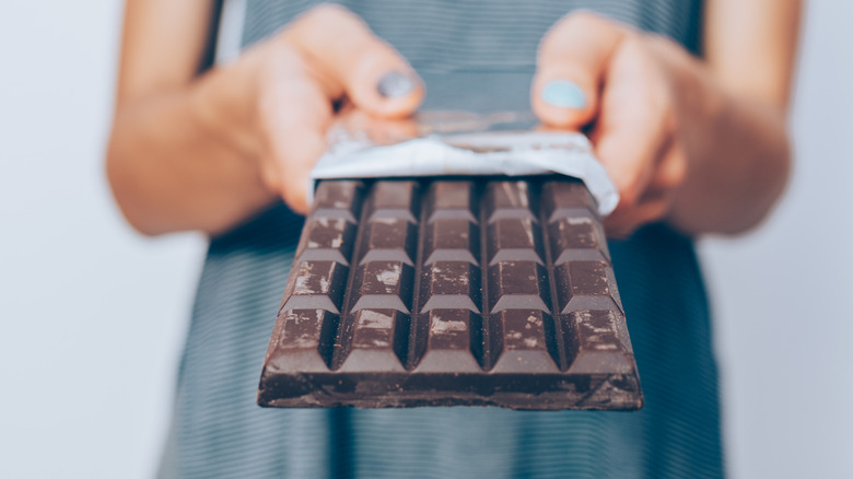 person holding unwrapped dark chocolate