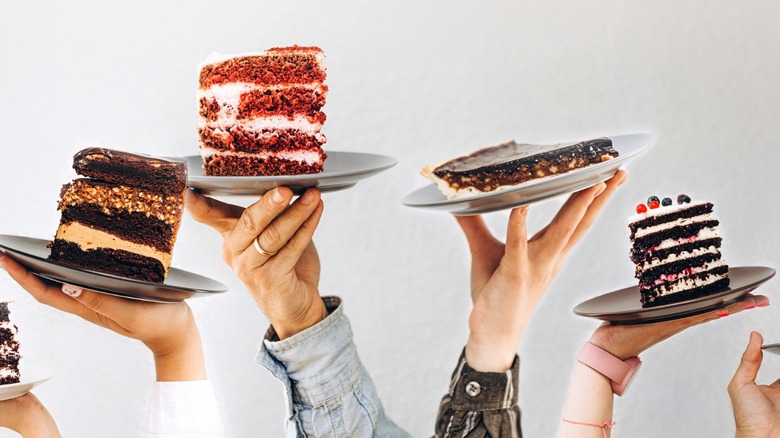 Hands holding cakes on plates