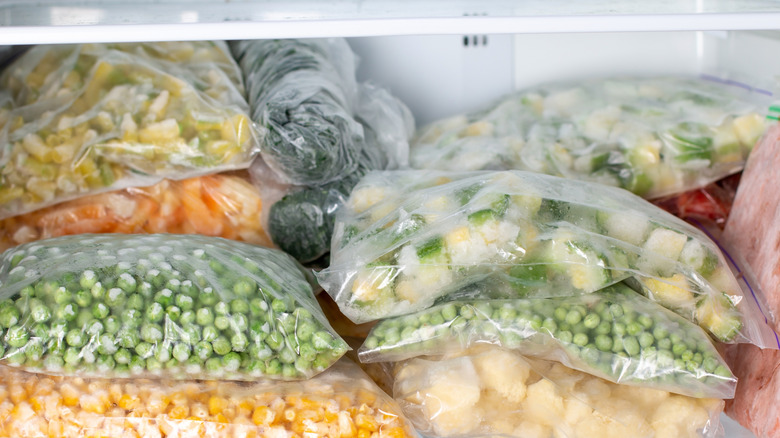 Clear bags of frozen vegetables stacked in a freezer
