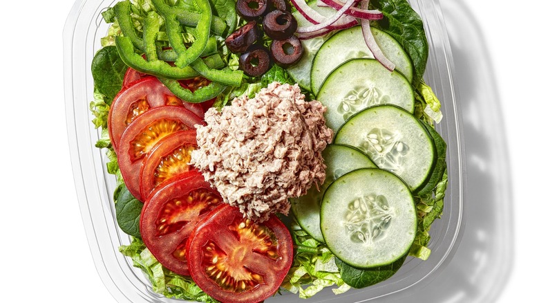 Subway salad with tomatoes, cucumbers, green peppers, black olives, and mound of tuna salad, over iceberg lettuce
