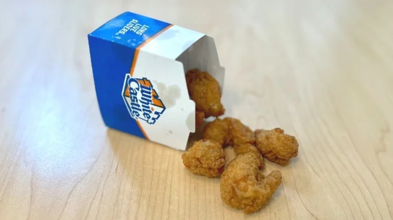 Takeout box of White Caste shrimp nibblers on wooden surface