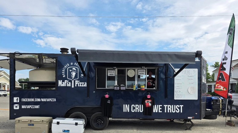 Navy Mafia Pizza truck with t-shirts hanging outside