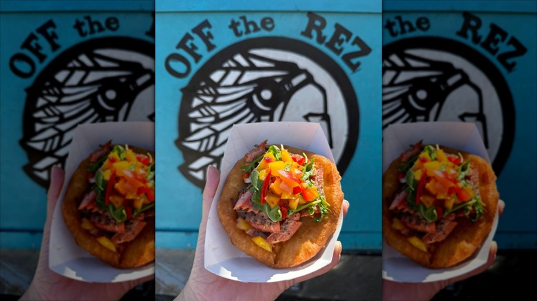 Hand holding Indian taco in front of Off the Rez logo