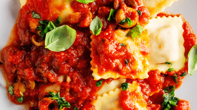 Plate of ravioli with marinara and basil garnish