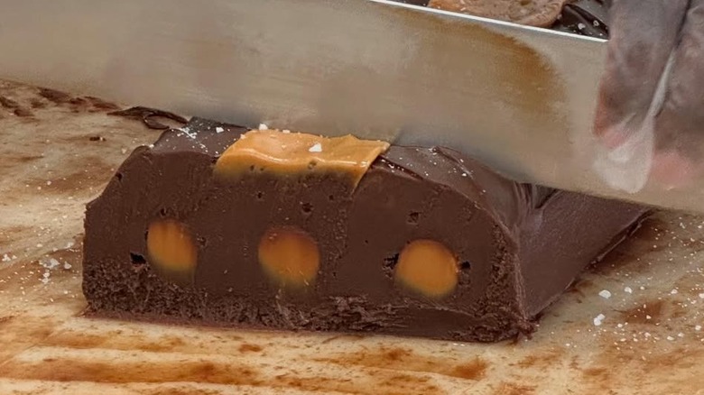 Hands slicing loaf of fudge at Joann's in Michigan