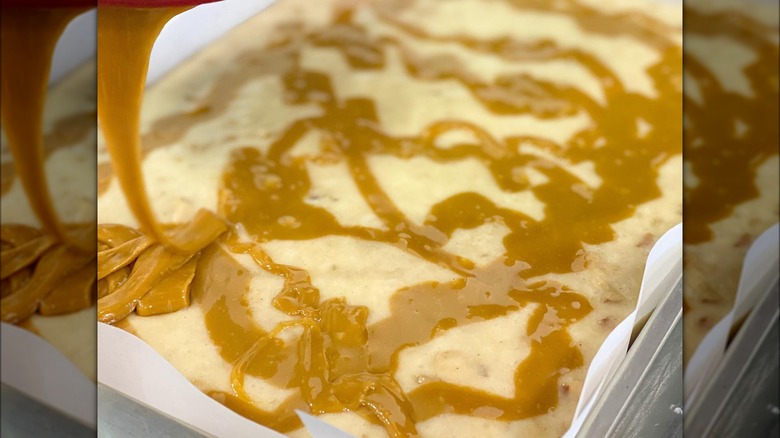 Drizzling topping onto big slab of white fudge