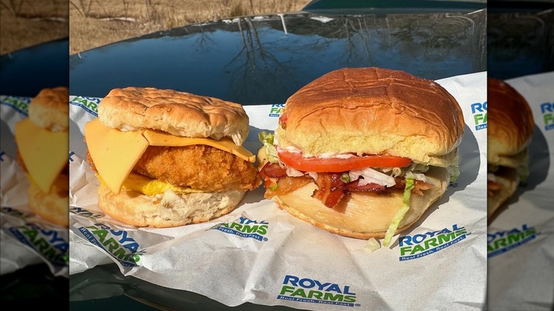 Two Royal Farms chicken sandwiches, one with egg and cheese on a biscuit, the other with bacon, lettuce, and tomato on a roll