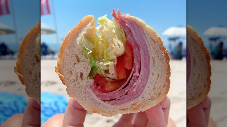 Close-up of an Italian hoagie with deli meat, lettuce, and tomato on a roll