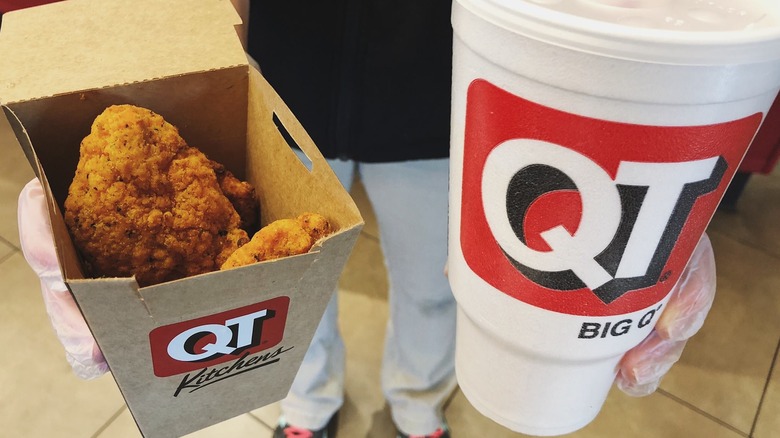 hands holding a large QT drink and a box of QT Kitchens tenders