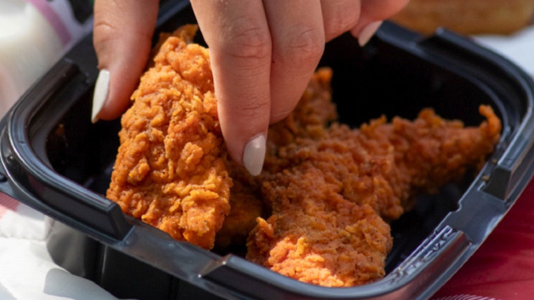 hand reaching into a tray of Weigel's Dippin' Chicken