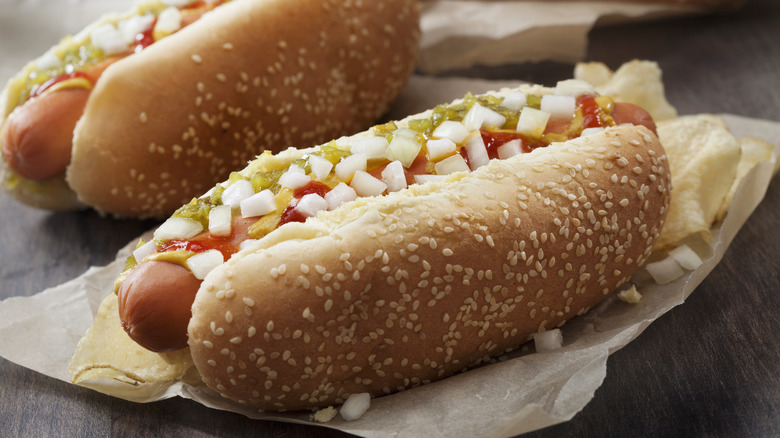 Hot dog with sesame seed bun topped with ketchup, mustard, onions, and relish