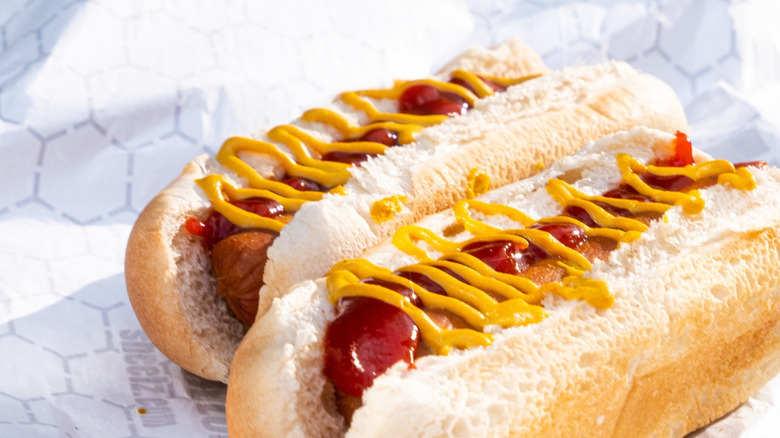 Two hot dogs with ketchup and mustard on paper wrapper