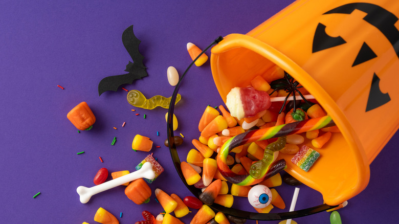 Pumpkin candy bucket spilling onto purple background