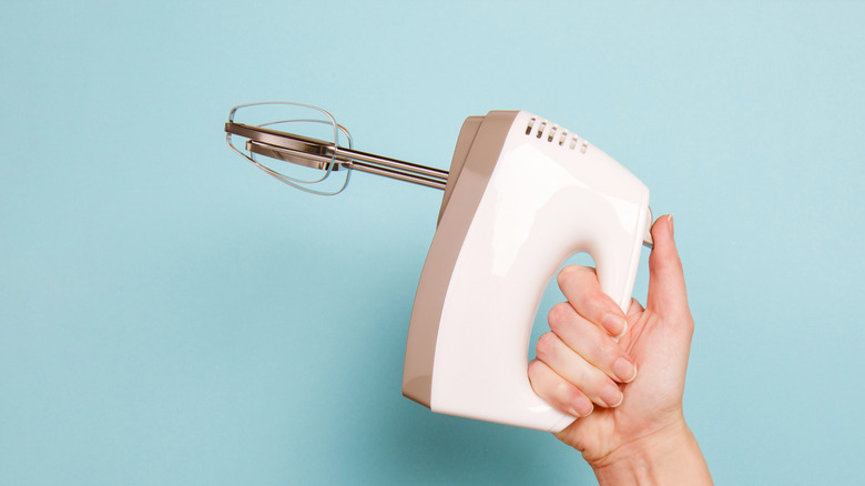 White hand mixer blue background