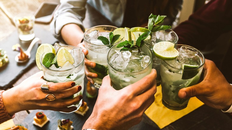 Hands holding mojito cocktails 