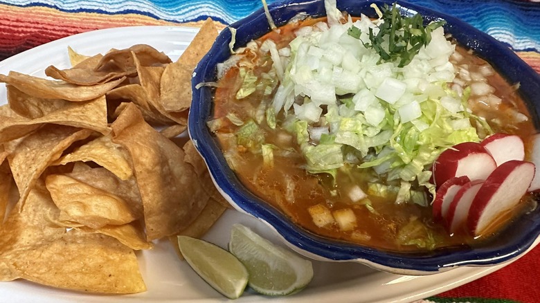 a bowl of pozole with a side of tortilla chips