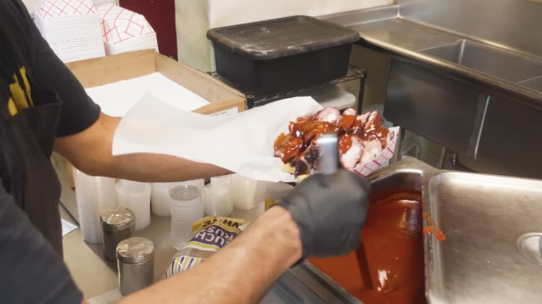 hand holding paper rib tip boat with bbq sauce