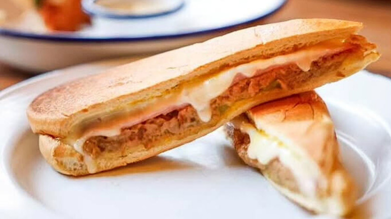 Manolito's Cuban sandwich cut in half and served on a white plate