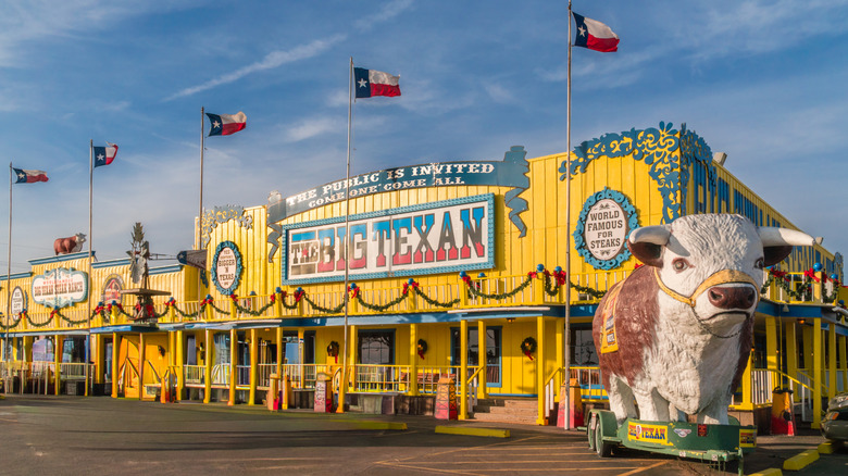 Large yellow building with five Texas flags spaced along the front
