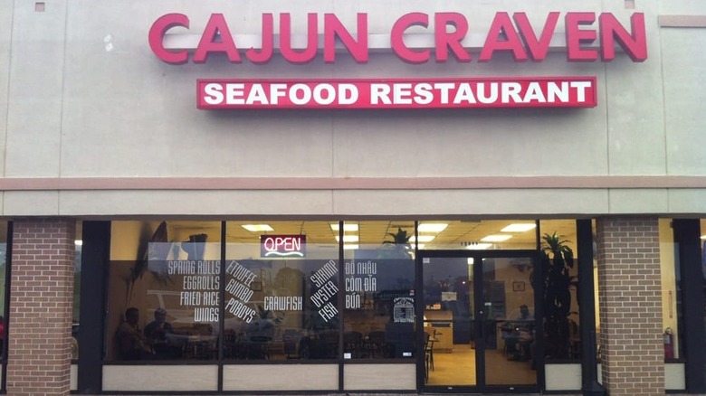 A strip mall restaurant with red block letters advertising the name Cajun Craven