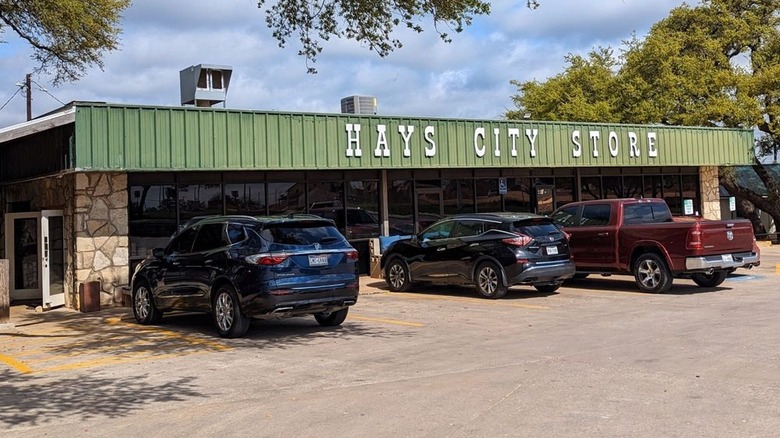 Trucks and SUVs parked in front of stone building with a green awning.