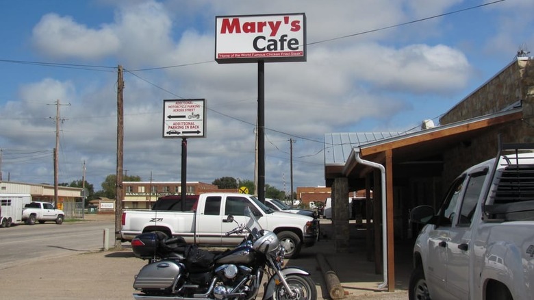 Pick up trucks and trailers fill a parking lot in front of Mary's Cafe