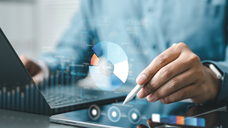 A man makes calculations using a tablet and computer.