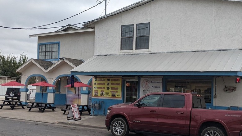 A blue and white two-story building with a truck outside
