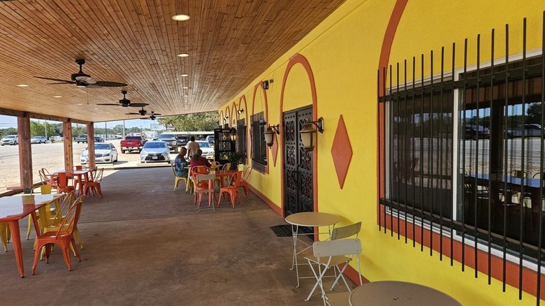 The exterior of an orange and yellow restaurant with outdoor seating