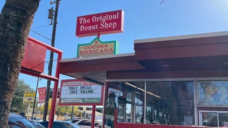 A roadside marquee in front of a drive thru donut shop.