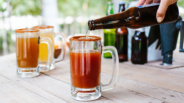 hand pouring beer into michelada