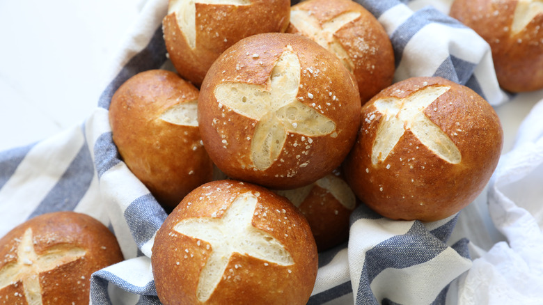 Homemade pretzel buns on a basket over a blue and white cloth
