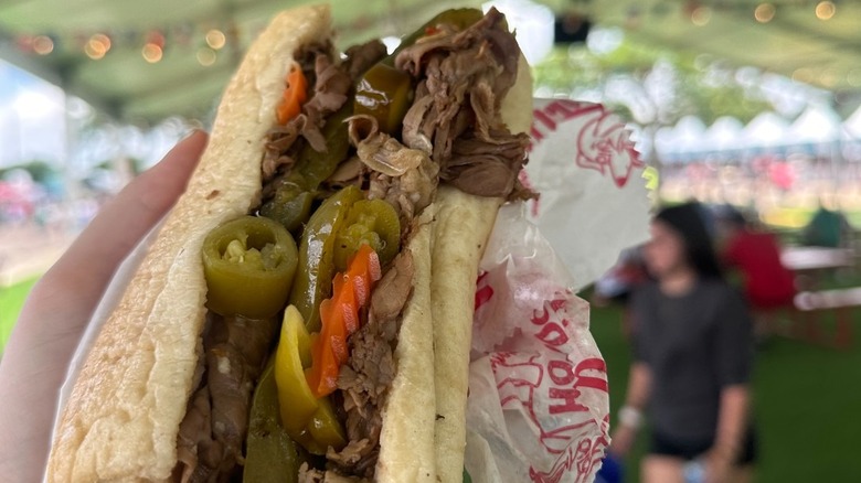 A hand holding an Italian beef sandwich from Portillo's