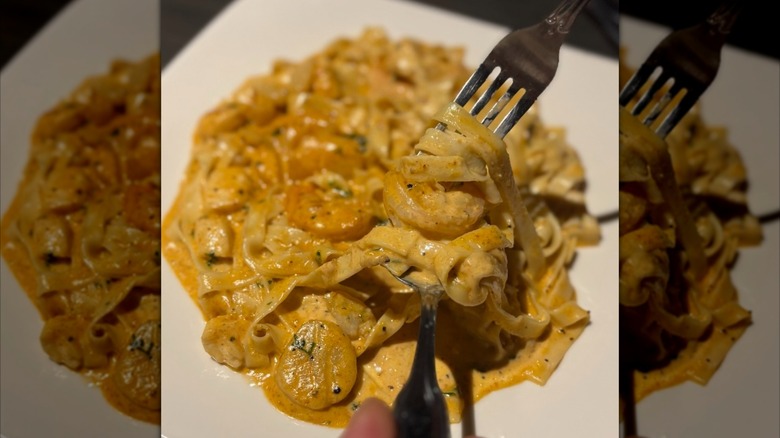 Fork and spoon digging into shrimp pasta