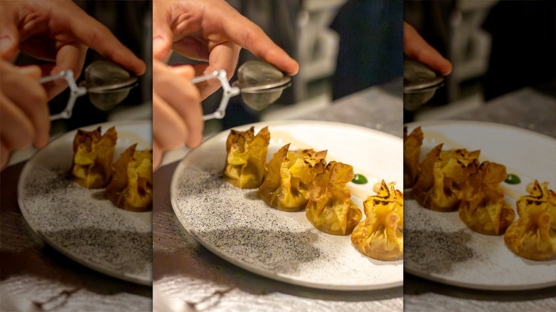 Hands dusting four dumplings on a plate