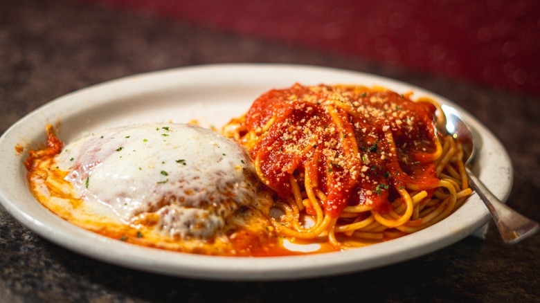 Spaghetti covered in marinara sauce with cheese-covered chicken