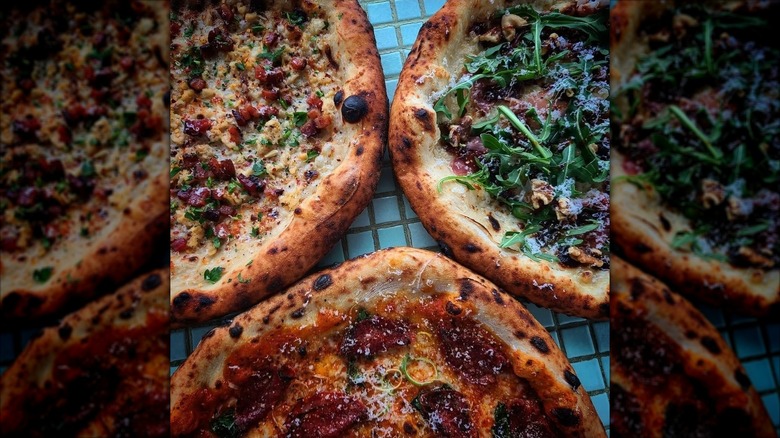 Three pizzas on a blue tiled table