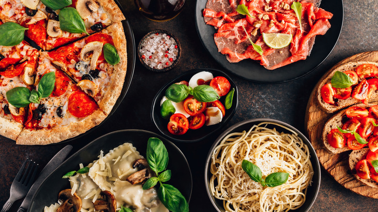 A variety of Italian dishes, including pizza, prosciutto, ravioli, and bruschetta