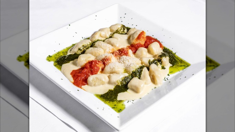 Gnocchi with tomato sauce, cream, and pesto, topped with grated cheese
