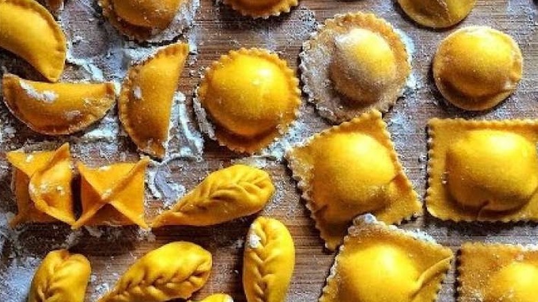 Table with different types of dry pasta, including raviolli, agnolotti, conchiglie, pansotti and more