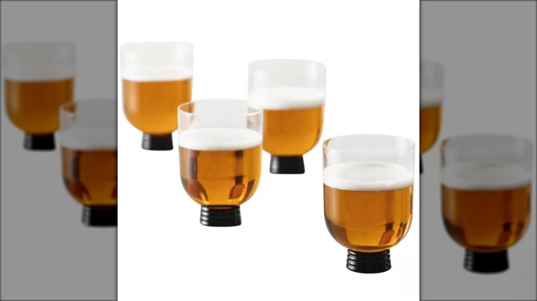 Four glasses with black bases filled with beer
