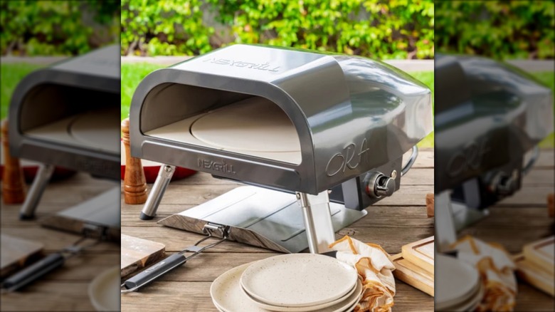 Small pizza oven on wooden picnic table with plates