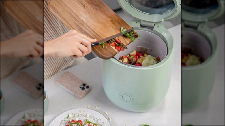 person depositing food scraps into automatic composter