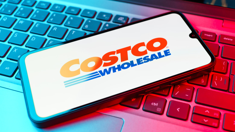 smartphone displaying Costco logo lays atop a computer keyboard